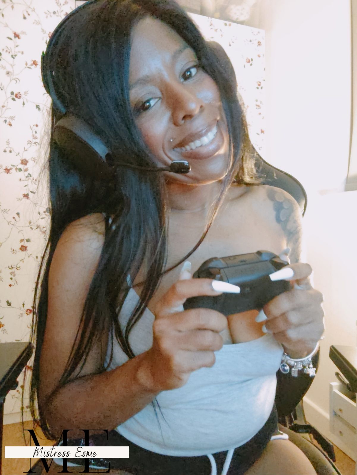 Mistress Esme in her gaming chair with headset on and controller in her hand.